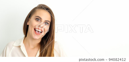 Portrait of a young caucasian happy woman wearing white shirt smiling with open mouth against the white background 94082412