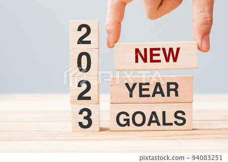 hand holding wooden block with text 2023 NEW YEAR NEW GOALS on table background. Resolution, strategy, solution, business and holiday concepts 94083251