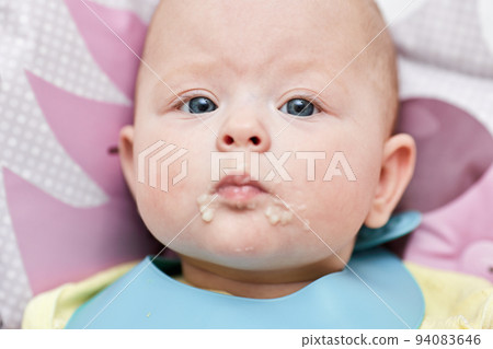 baby girl after eating porridge on baby chair 94083646