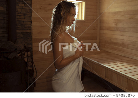 A young woman relaxes and sweats in a hot sauna - Stock Photo [94083870]  - PIXTA