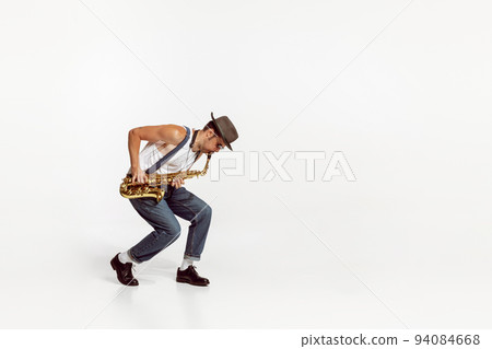Portrait of stylish man in hat and suglasses playing saxophone , performing isolated over white background. Jazz performer 94084668