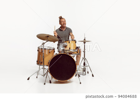 Portrait of funny emotive man playing drums, performing isolated over white background. Bass, rock music 94084688