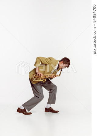 Portrait of young man in stylish yellow jacket playing saxophone isolated over white background. Jazz festival Portrait of young man in stylish yellow jacket playing saxophone isolated over white background. Jazz festival 94084700