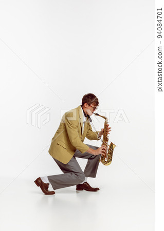 Portrait of young man in stylish yellow jacket playing saxophone isolated over white background. Expressive music Portrait of young man in stylish yellow jacket playing saxophone isolated over white background. Expressive music 94084701