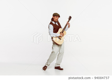 Portrait of stylish man playing guitar, performing isolated over white studio background. Making lovely sounds 94084737
