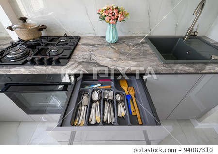 High angle frontal closeup view to open drawer of grey and white modern domestic kitchen 94087310