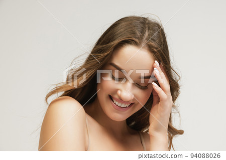 Closeup portrait of young cheerful beautiful girl with curly long hair smiling and looking at camera with happy and relaxed face expression Closeup portrait of young cheerful beautiful girl with curly long hair smiling and looking at camera with happy and relaxed face expression 94088026