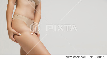 Cropped image of slim young beautiful tanned woman in lingerie posing isolated over grey studio background. Natural beauty, anti-cellulite treatment concept. 94088044