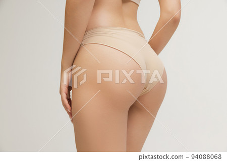 Cropped image of slim young beautiful tanned woman in lingerie posing isolated over grey studio background. Natural beauty, anti-cellulite treatment concept. 94088068