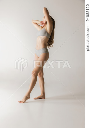 Young beautiful slim woman in grey cotton underwear isolated over gray studio background. Wellness, wellbeing, fitness, diet, natural beauty of female body Young beautiful slim woman in grey cotton underwear isolated over gray studio background. Wellness, wellbeing, fitness, diet, natural beauty of female body 94088120