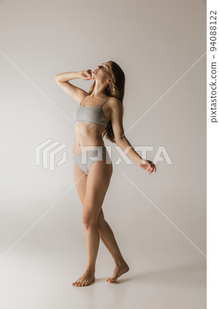 Slim sportive young woman in underwear on grey background. Fitness, diet, skin and body care. Slim sportive young woman in underwear on grey background. Fitness, diet, skin and body care. 94088122