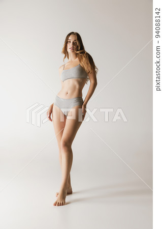 Young beautiful slim woman in grey cotton underwear isolated over gray studio background. Wellness, wellbeing, fitness, diet, natural beauty of female body Young beautiful slim woman in grey cotton underwear isolated over gray studio background. Wellness, wellbeing, fitness, diet, natural beauty of female body 94088142