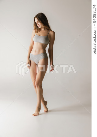Young beautiful slim woman in grey cotton underwear isolated over gray studio background. Wellness, wellbeing, fitness, diet, natural beauty of female body 94088174