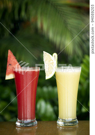 mixed organic fresh fruit juices in cafe with.garden background 94089203