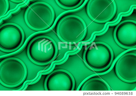 Relief surface of green silicon anti stress sensory pop it toy with with bumps and pits close up. Popular calming toy for hyperactive kids. View from above. Relief surface of green silicon anti stress sensory pop it toy with with bumps and pits close up. Popular calming toy for hyperactive kids. View from above. 94089638