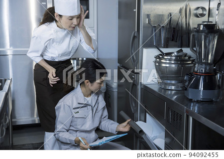 一名女工與一名餐廳員工一起檢查廚房，並展示了維護圖像 94092455