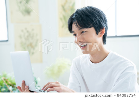 Young man using laptop in bright room 94092754
