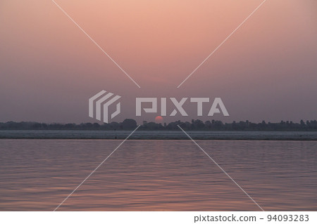 India Varanasi early morning Ganges river and the sky dyed orange in the morning sun India Varanasi early morning Ganges river and the sky dyed orange in the morning sun 94093283
