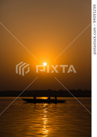 印度瓦拉納西恒河上漂浮的一艘船，天空被晨光染成橙色 94093299