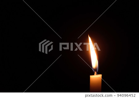 White candle flame closes upon a black background, Candle Burning in the Dark with lights glow, The burning candle's flame with light glow background a symbol of the Christian faith. 94096452