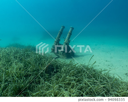Antique cannons on a sandy sea floor. Turquoise water in the background 94098335