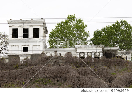 Abandoned railway station building. The territory of the station is overgrown with plants 94098629