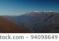 Gorgeous bird's eye view on the caucasus mountains in fall season. scenic lansscape of rosa khutor village drowning in forested mountain range with snowy peaks. 94098649