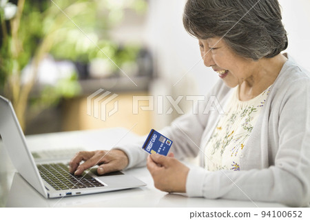 Senior woman enjoying online shopping on a computer Senior woman enjoying online shopping on a computer 94100652
