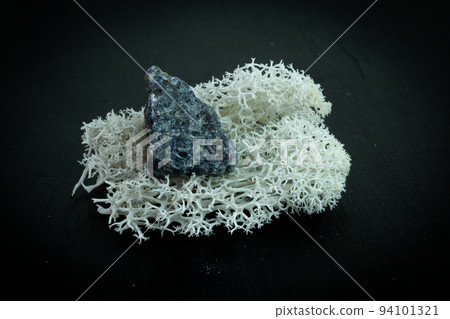 Granite. Natural mineral stone on a black background surrounded by moss. Mineralogy, geology, magic, semi-precious stones and samples of minerals. Close-up macro photo 94101321