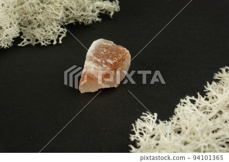 Halite or rock salt from Pakistan. Natural mineral stone on a black background surrounded by moss. Mineralogy, geology, magic, semi-precious stones and samples of minerals. Close-up macro photo 94101365
