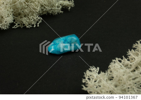 Howlite or turquoise imitation from Republic of South Africa RSA. Natural mineral stone on a black background surrounded by moss. Mineralogy, geology, magic, semi-precious stones samples of minerals. 94101367