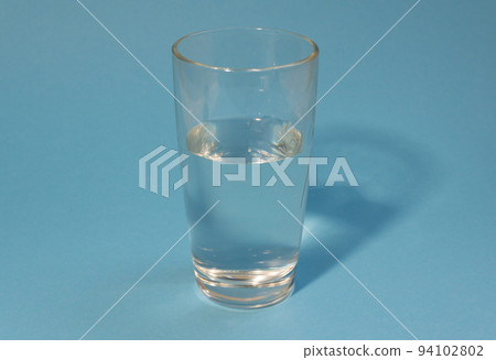 Half-filled glass of clean cold water on a light blue background. Healthy life, proper nutrition, drink plenty of water. Half-filled glass of clean cold water on a light blue background. Healthy life, proper nutrition, drink plenty of water. 94102802