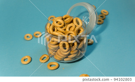 Yellow small sushki bagels in glassware on a blue background. Yellow small sushki bagels in glassware on a blue background. 94102803