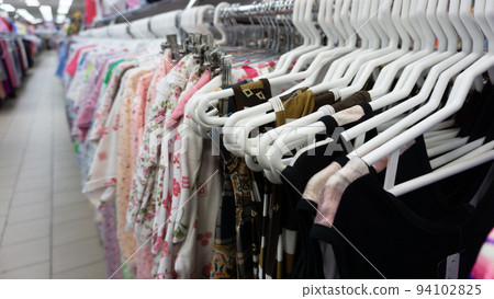 A row of hanging women's clothing in a store. Large selection of dresses on hangers. Shopping center, shopping. A row of hanging women's clothing in a store. Large selection of dresses on hangers. Shopping center, shopping. 94102825