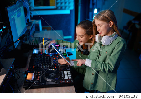 Young girls adjusting sound on sound mixer in radio station Young girls adjusting sound on sound mixer in radio station 94105138