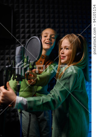Happy girls wearing headphones singing in record studio 94105154