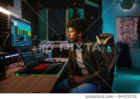 Young man on chair front of monitor in studio of records 94105238