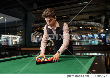 Man putting billiard balls in triangle rack 94105373