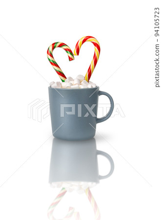 Cocoa with marshmallows and two heart-shaped Candy canes in a gray cup isolated on a white background with reflection. A Christmas gift, a traditional drink for a cozy winter evening. Cocoa with marshmallows and two heart-shaped Candy canes in a gray cup isolated on a white background with reflection. A Christmas gift, a traditional drink for a cozy winter evening. 94105723