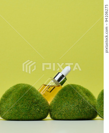 Glass transparent bottle with pipette and yellow oil on green moss Glass transparent bottle with pipette and yellow oil on green moss 94106275