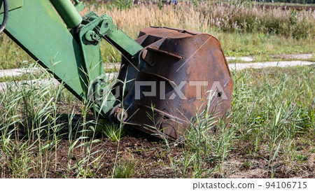 green excavator, green grass in the swamp on a very sunny day. Rusty chains and cup green excavator, green grass in the swamp on a very sunny day. Rusty chains and cup 94106715