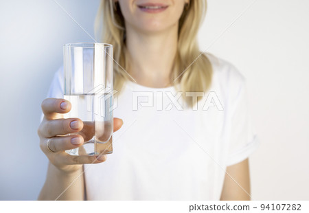 The concept of maintaining water balance in the body. The girl holds a glass of water in front of her. 94107282