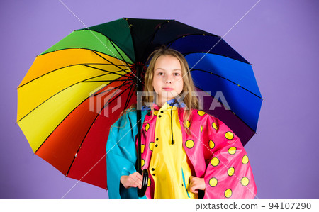 Waterproof accessories make rainy day cheerful and pleasant. Kid girl happy hold colorful umbrella wear waterproof cloak. Waterproof accessories for children. Enjoy rainy weather with proper garments 94107290