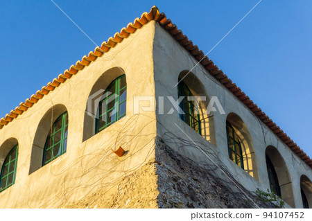 Building corner with green arched windows and tiled roof 94107452
