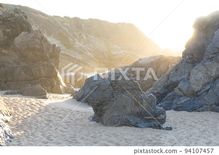 Haze in the rocks on the ocean in the rays of the setting sun Haze in the rocks on the ocean in the rays of the setting sun 94107457