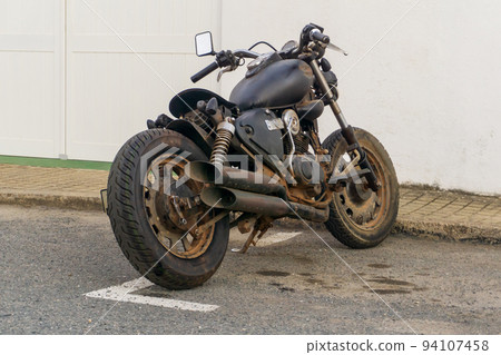 Classic black motorcycle parked by the roadside Classic black motorcycle parked by the roadside 94107458