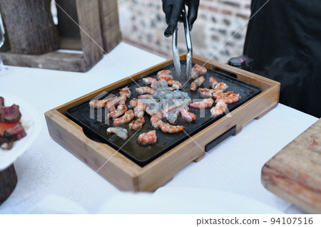 The chef prepares the shrimps on the plancha The chef prepares the shrimps on the plancha 94107516