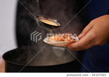 The seller pours a white sauce on the scallops 94107985
