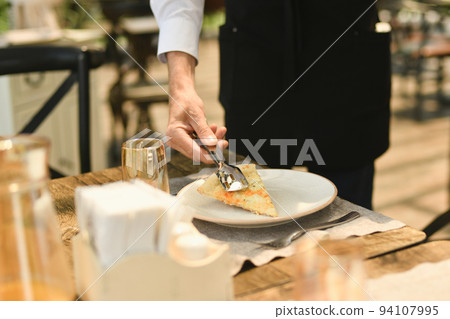 The waiter punishes a piece of cheese on a plate The waiter punishes a piece of cheese on a plate 94107995