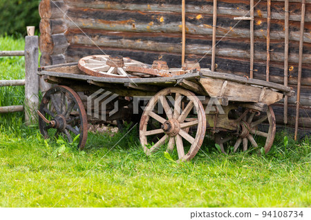 Old wooden wagon stands on green grass 94108734